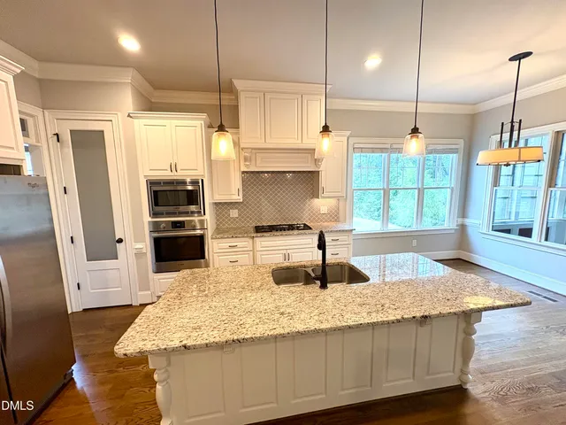 a kitchen with kitchen island granite countertop a sink a counter and stainless steel appliances