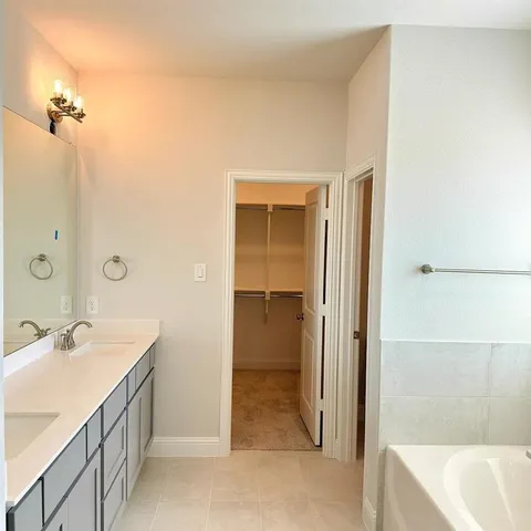 a bathroom with a double vanity sink a mirror and a bathtub