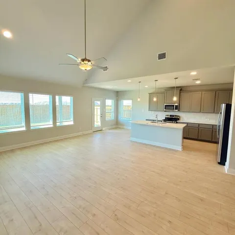 a view of an empty room with kitchen view and a window