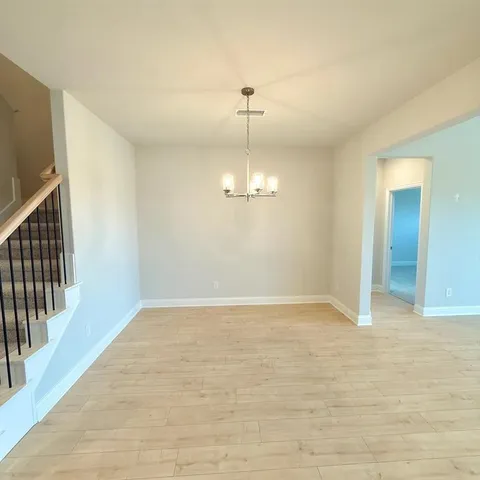 an empty room with chandelier fan and windows