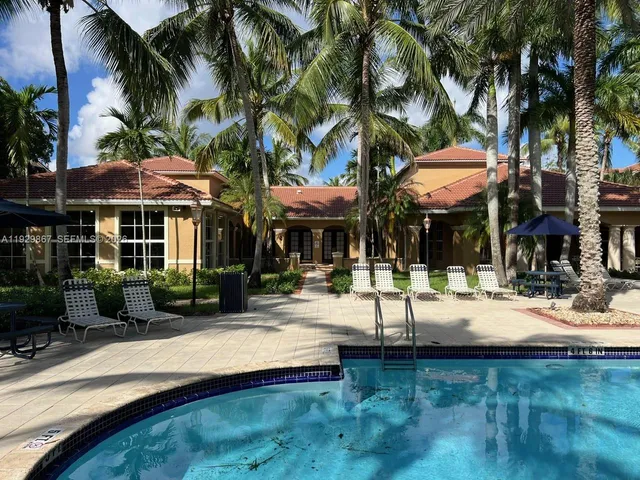 a view of a white house in a big yard with palm trees