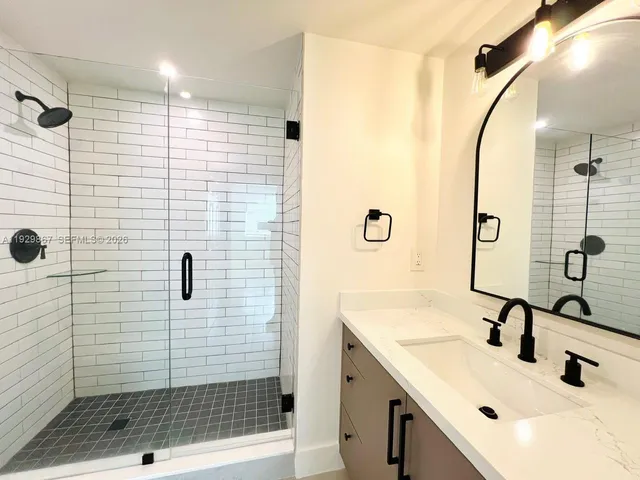 a bathroom with a sink a glass door shower and a mirror