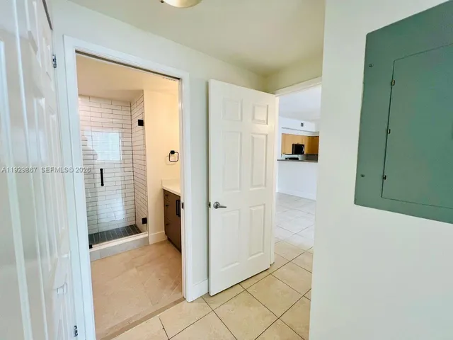 a view of a hallway with white cabinets and entryway