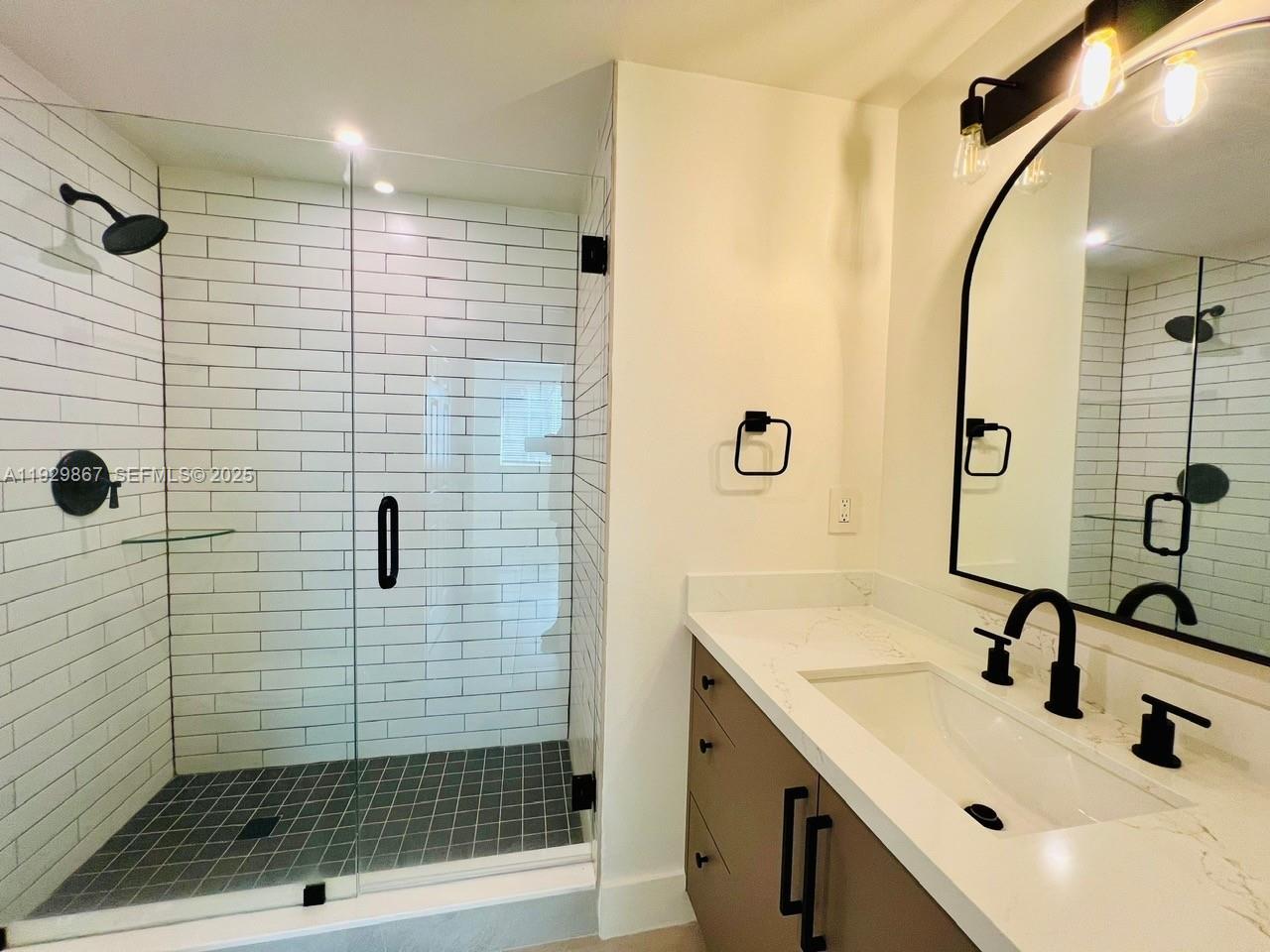 8000 North Nob Hill Road, Unit 204 Tamarac, FL 33321 - Photo 10 of 27 a bathroom with a sink a glass door shower and a mirror