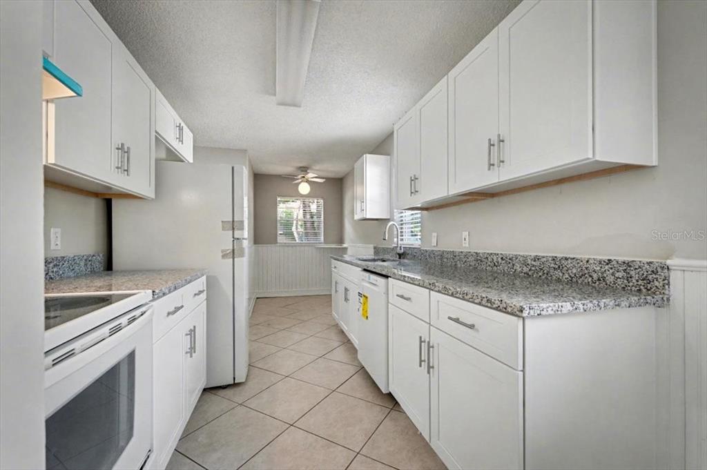 173 North Ridgewood Avenue Ormond Beach, FL 32174 - Photo 13 of 33 a kitchen with granite countertop white cabinets and white appliances