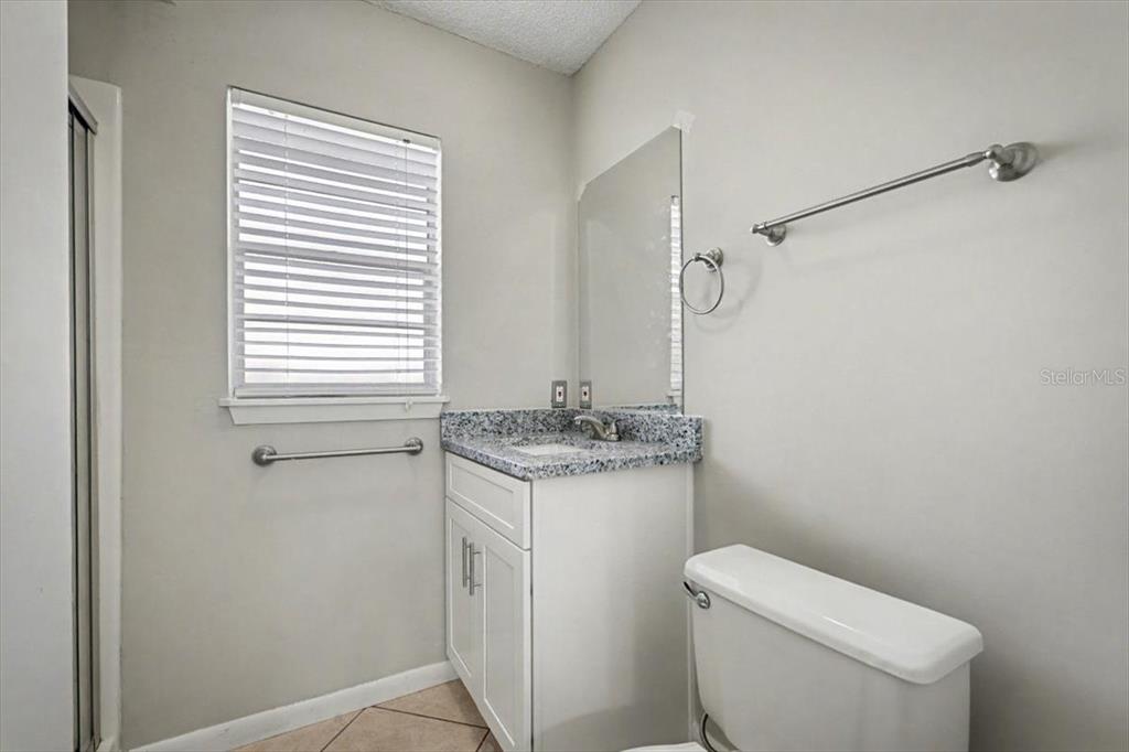173 North Ridgewood Avenue Ormond Beach, FL 32174 - Photo 22 of 33 a bathroom with a granite countertop toilet a sink and a window