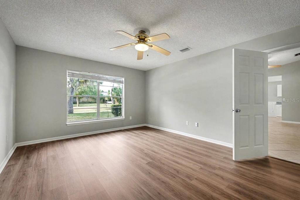 173 North Ridgewood Avenue Ormond Beach, FL 32174 - Photo 28 of 33 an empty room with wooden floor fan and windows
