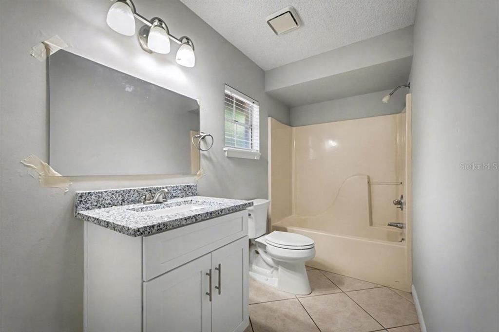 173 North Ridgewood Avenue Ormond Beach, FL 32174 - Photo 29 of 33 a bathroom with a granite countertop sink a toilet a mirror and shower