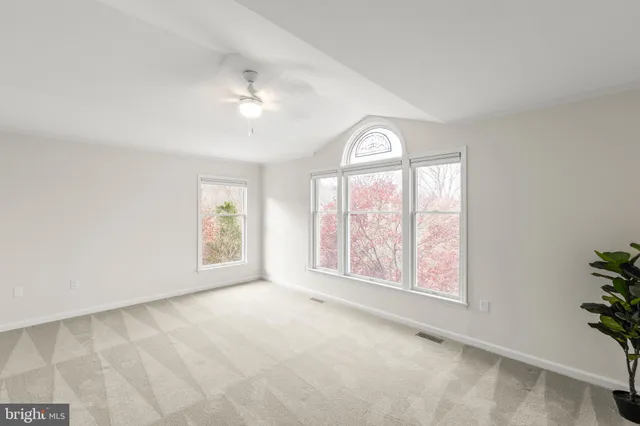 an empty room with windows and ceiling fan