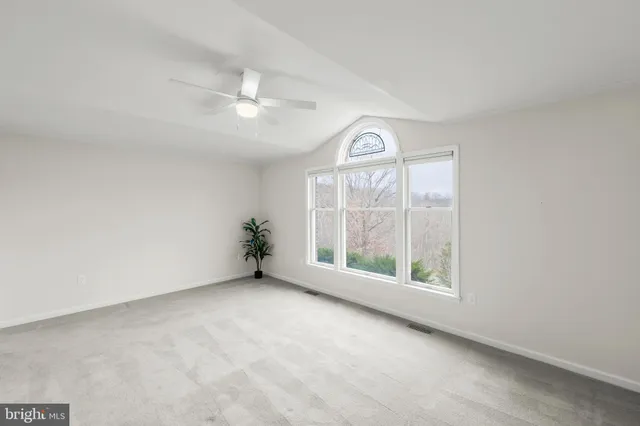 an empty room with a ceiling fan and window