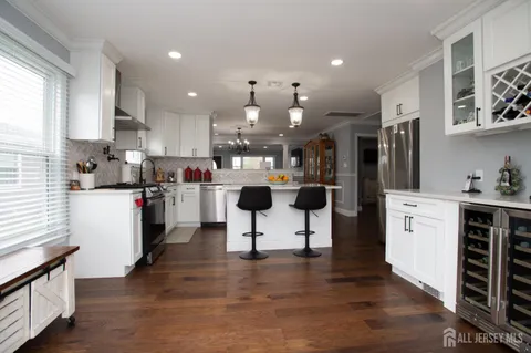 a kitchen view with stainless steel appliances kitchen island granite countertop a refrigerator and a stove top oven