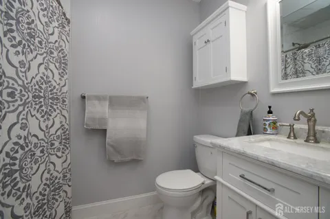a bathroom with a granite countertop toilet and sink