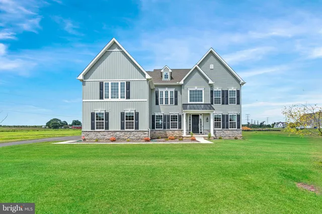 a front view of a house with garden and trees