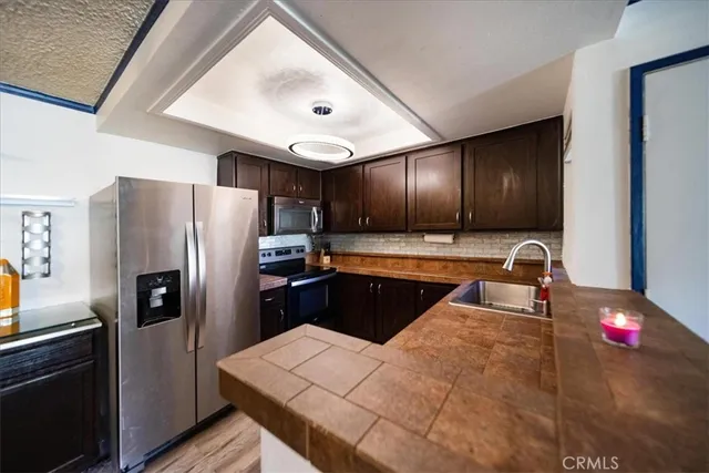a kitchen with stainless steel appliances kitchen island granite countertop a refrigerator and a sink