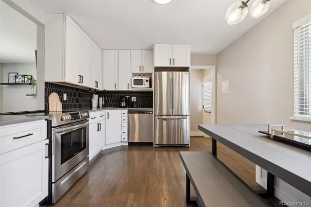 a kitchen with stainless steel appliances a refrigerator a sink and wooden floors