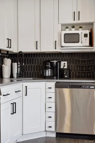 a kitchen with white cabinets and black appliances