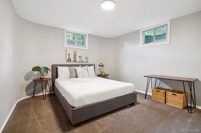 a bed sitting in a bedroom next to a window with a lamp