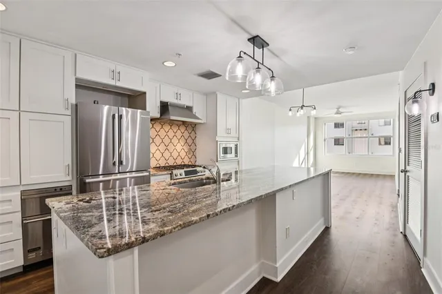 a large kitchen with granite countertop a large counter top appliances and cabinets