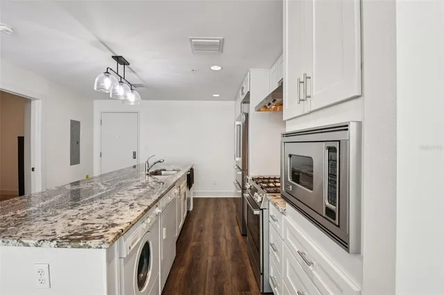 a kitchen with granite countertop stainless steel appliances sink stove microwave and cabinets