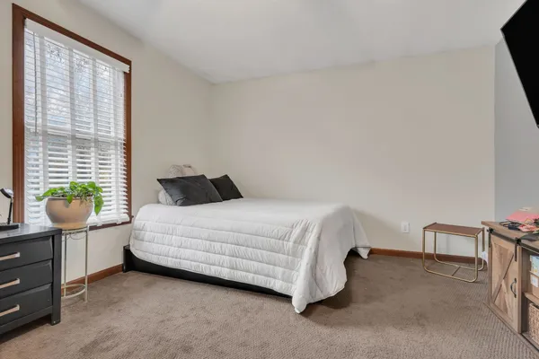 a bedroom with a bed a dresser and next to a window