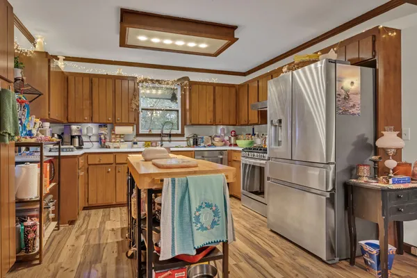 a kitchen with stainless steel appliances granite countertop a refrigerator a sink dishwasher a stove and a dining table with wooden floor