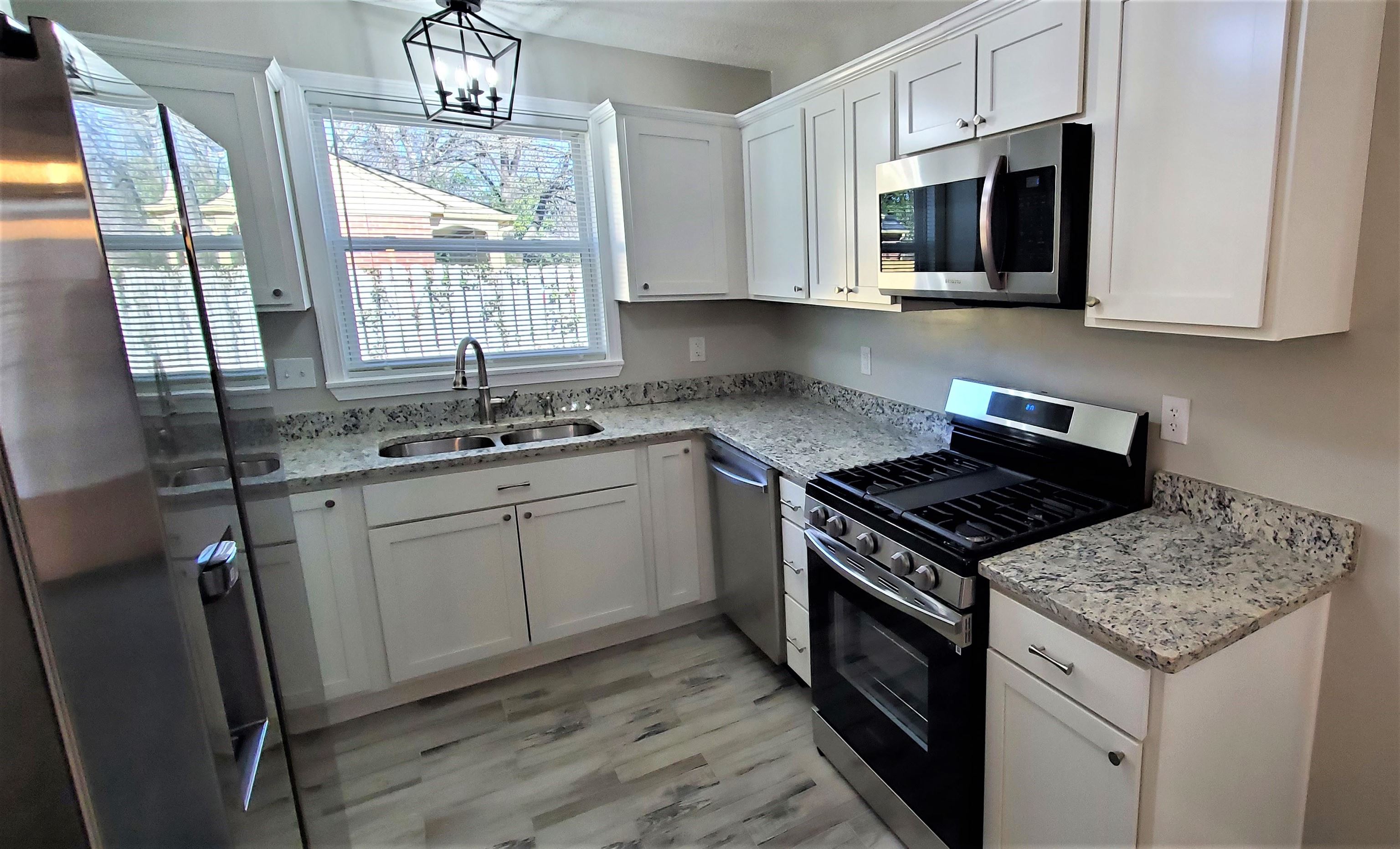 1077 Colonial Road Memphis, TN 38117 - Photo 8 of 20 a kitchen with stainless steel appliances granite countertop a stove a sink dishwasher a microwave oven with cabinets and wooden floor