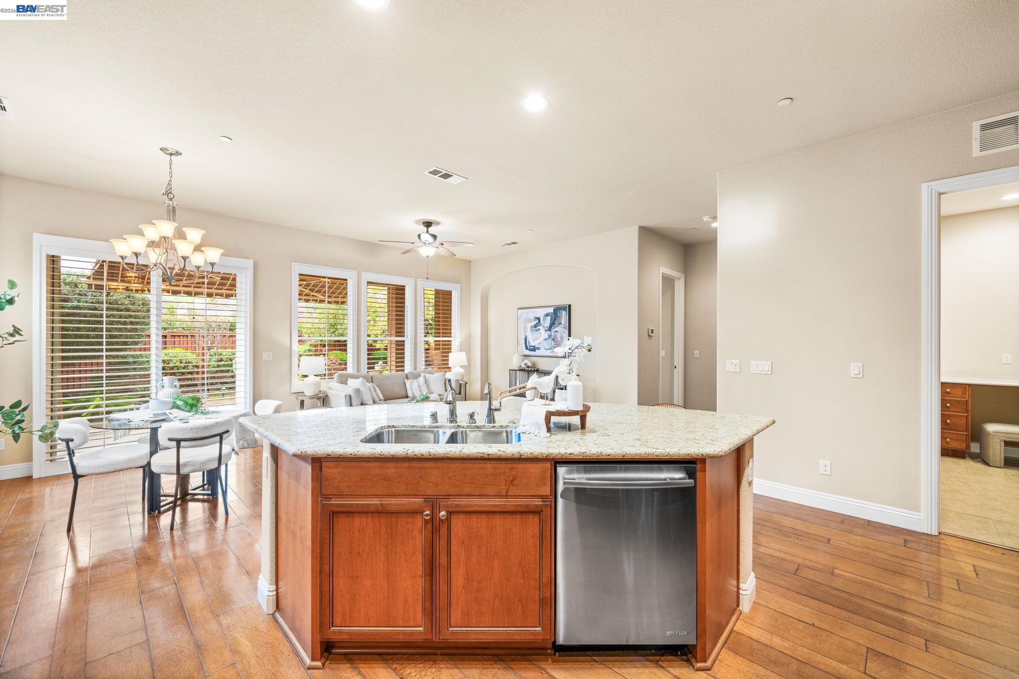 1033 Malbec Lane Brentwood, CA 94513 - Photo 12 of 37 a dining hall with stainless steel appliances granite countertop a sink dishwasher and a flat tv screen next to a large window with wooden floor