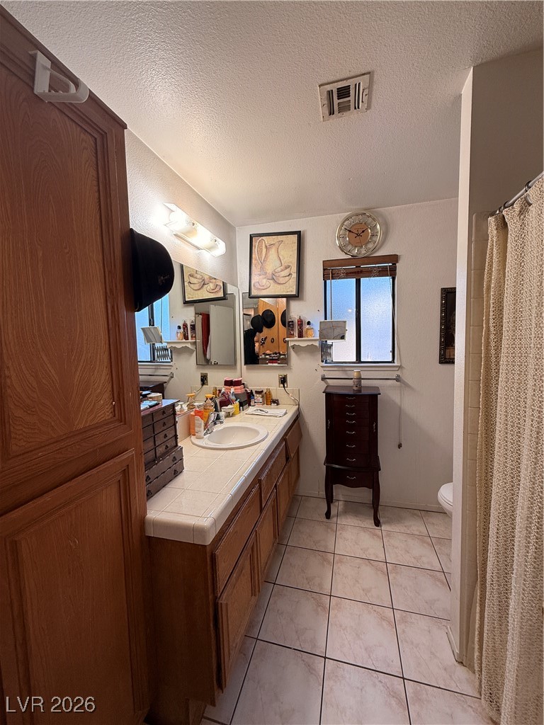 6425 West Eagle Point Road Las Vegas, NV 89108 - Photo 14 of 42 Full bathroom with a shower with curtain, vanity, a textured ceiling, and light tile patterned flooring