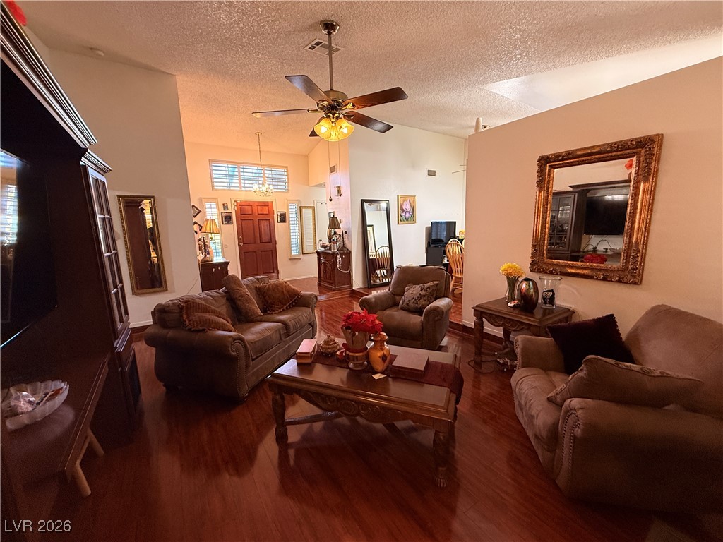 6425 West Eagle Point Road Las Vegas, NV 89108 - Photo 18 of 42 Living room featuring dark wood-style flooring, a textured ceiling, a ceiling fan, and high vaulted ceiling