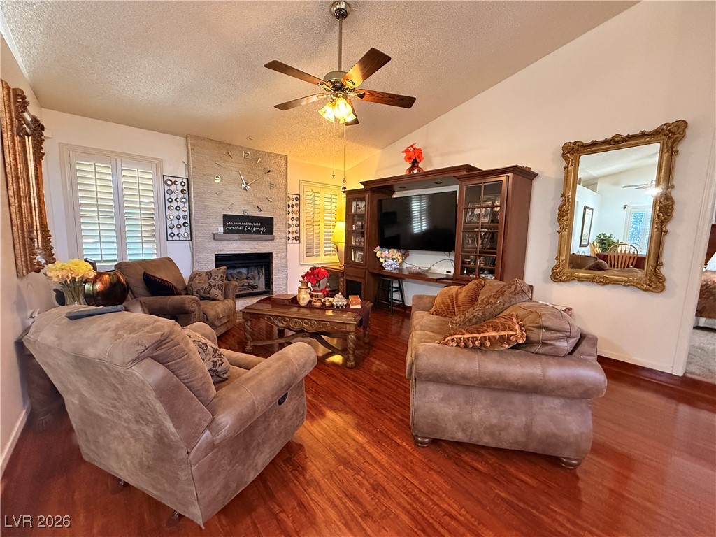 6425 West Eagle Point Road Las Vegas, NV 89108 - Photo 20 of 42 Living area with lofted ceiling, a textured ceiling, a fireplace, wood finished floors, and ceiling fan
