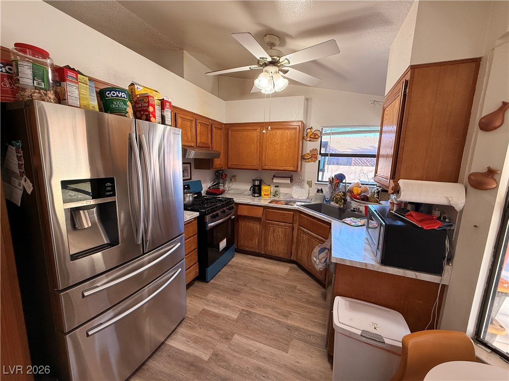 6425 West Eagle Point Road Las Vegas, NV 89108 - Photo 24 of 42 Kitchen featuring stainless steel appliances, brown cabinets, light countertops, lofted ceiling, and ceiling fan