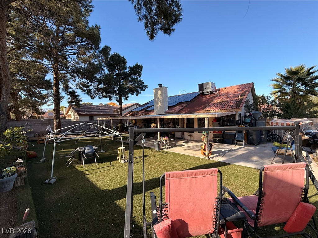 6425 West Eagle Point Road Las Vegas, NV 89108 - Photo 37 of 42 Rear view of house with a patio, a chimney, roof mounted solar panels, a fenced backyard, and a playground