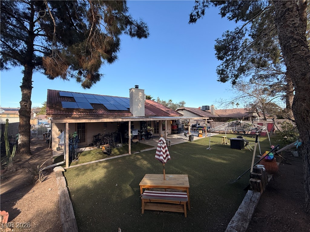 6425 West Eagle Point Road Las Vegas, NV 89108 - Photo 39 of 42 Back of house featuring a fenced backyard, solar panels, a patio area, and a chimney