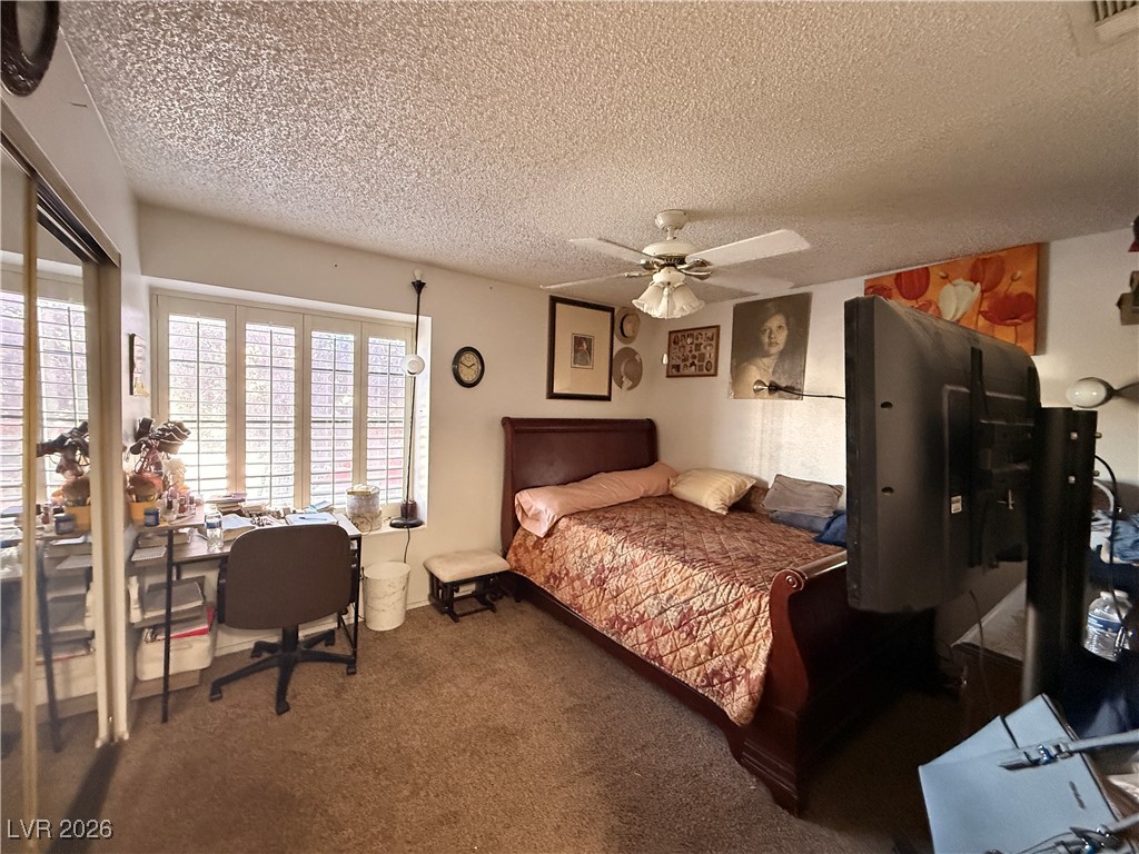 6425 West Eagle Point Road Las Vegas, NV 89108 - Photo 10 of 42 Bedroom featuring dark carpet, a ceiling fan, and a textured ceiling