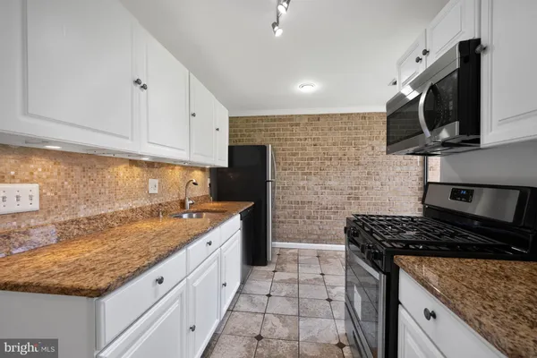 a kitchen with stainless steel appliances granite countertop a sink stove and microwave