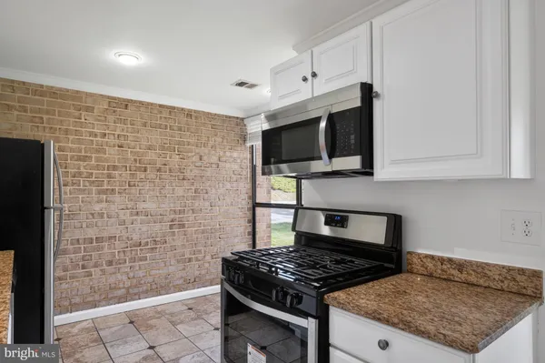 a kitchen with granite countertop a stove top oven microwave and cabinets