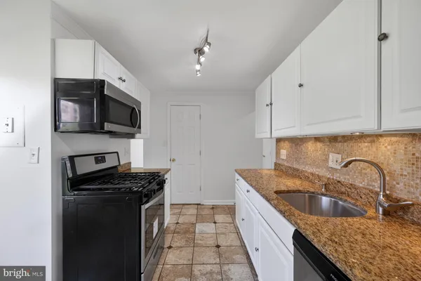 a kitchen with a sink stove top oven and cabinets