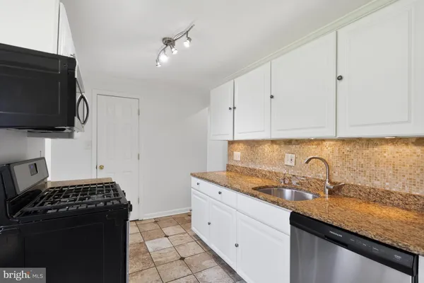 a kitchen with granite countertop a sink stove and cabinets
