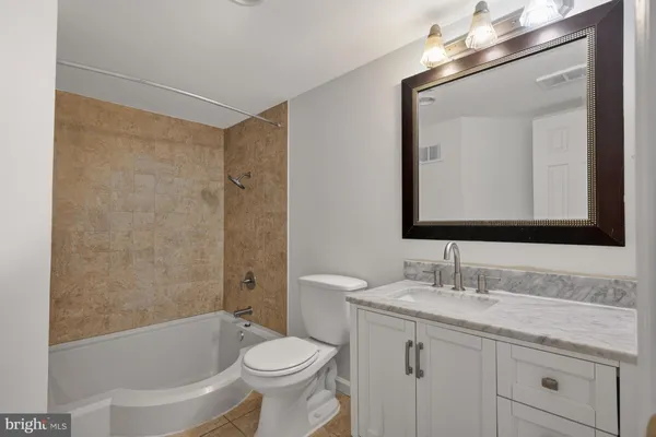 a bathroom with a toilet a sink a mirror a bathtub and vanity