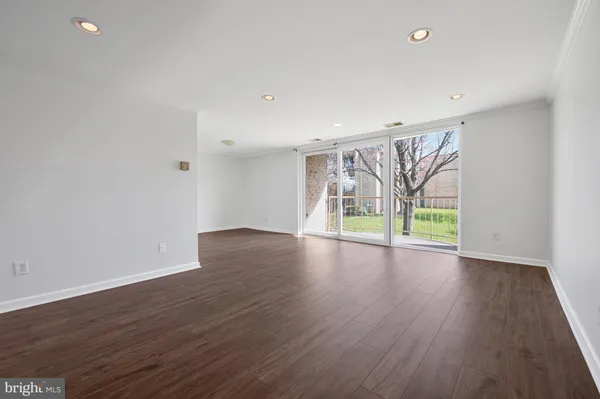 an empty room with wooden floor and natural light