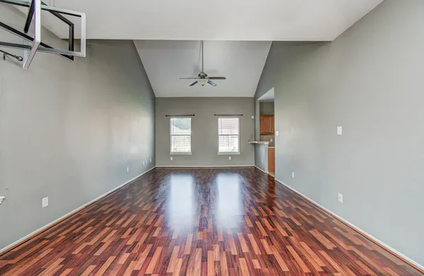 a view of empty room with wooden floor and fan