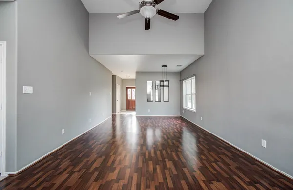 a view of a room with a ceiling fan and wooden floor