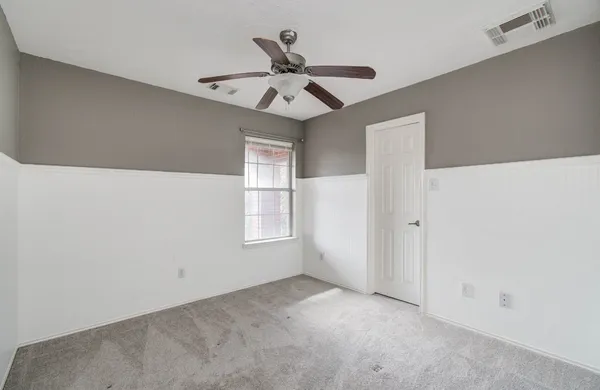 an empty room with a ceiling fan and carpet