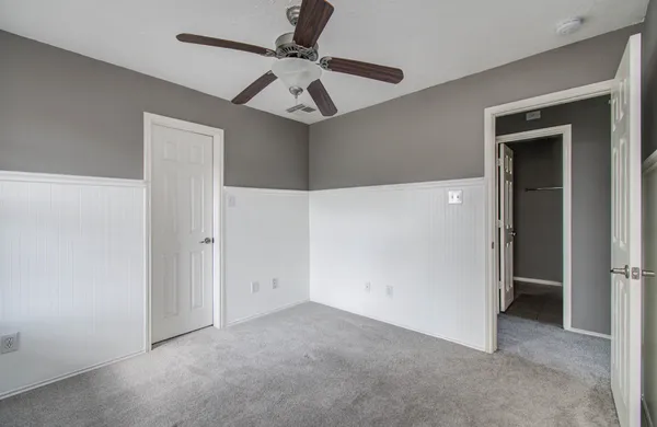 an empty room with a ceiling fan and carpet