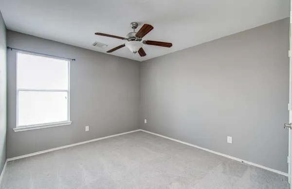 an empty room with a window and a fan