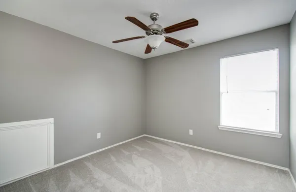 an empty room with a window and a ceiling fan