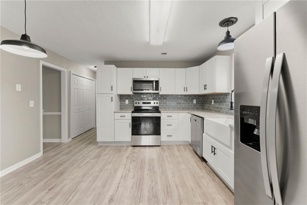 604 Fox Run Winder, GA 30680 - Photo 14 of 38 a kitchen with granite countertop a refrigerator oven a sink dishwasher and white cabinets with wooden floor