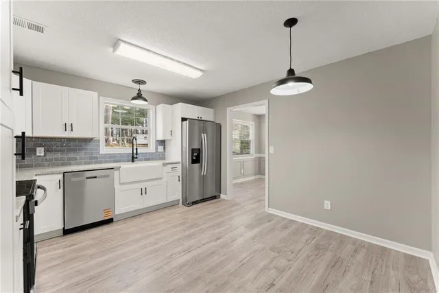 a open kitchen with stainless steel appliances granite countertop a refrigerator a sink dishwasher a stove and white countertops with wooden floor