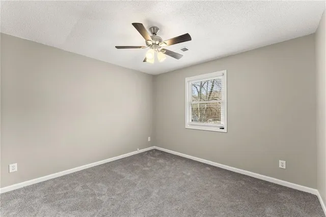 an empty room with window and ceiling fan