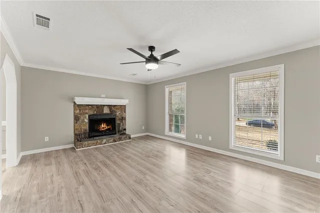 an empty room with windows a fireplace and wooden floor